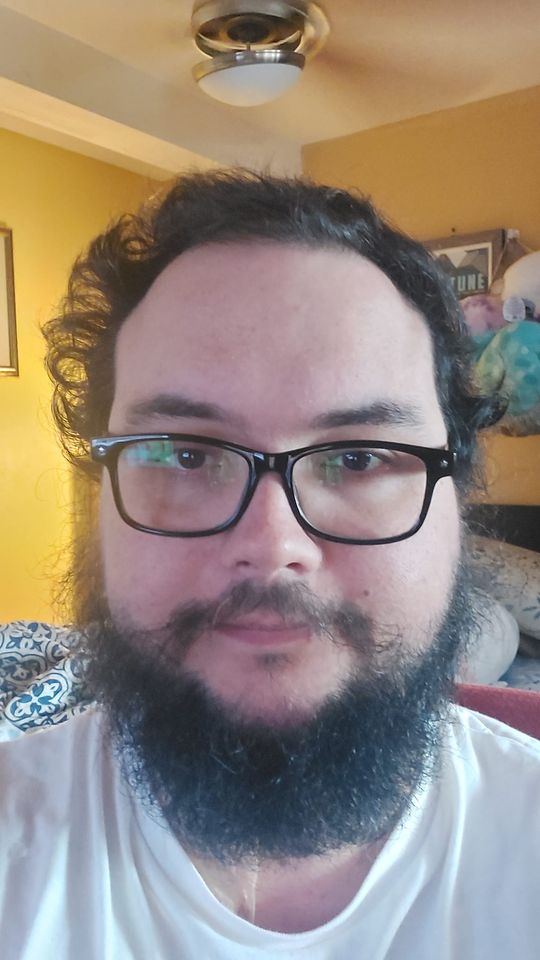 Photo of the same man from 2023, with full beard and noticibly curlier hair than before